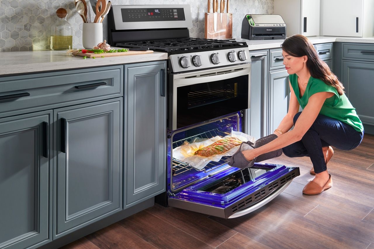 Woman using the lower oven on an LG range to bake a rack of ribs.