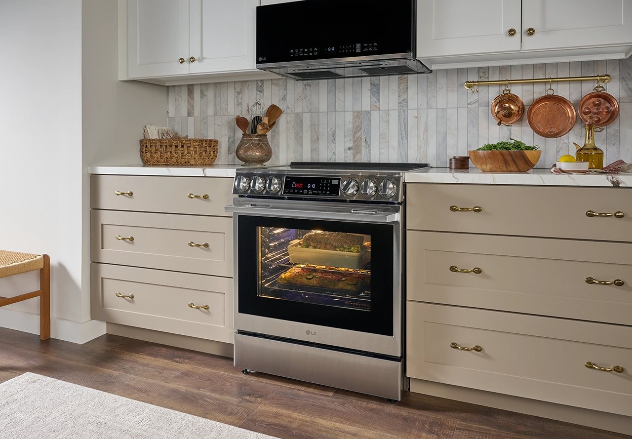 LG's Smart Low Profile Over-the-Range Microwave Oven with Sensor Cook in a mid-century style kitchen with vertical subway tile back splash and decorative copper molds.
