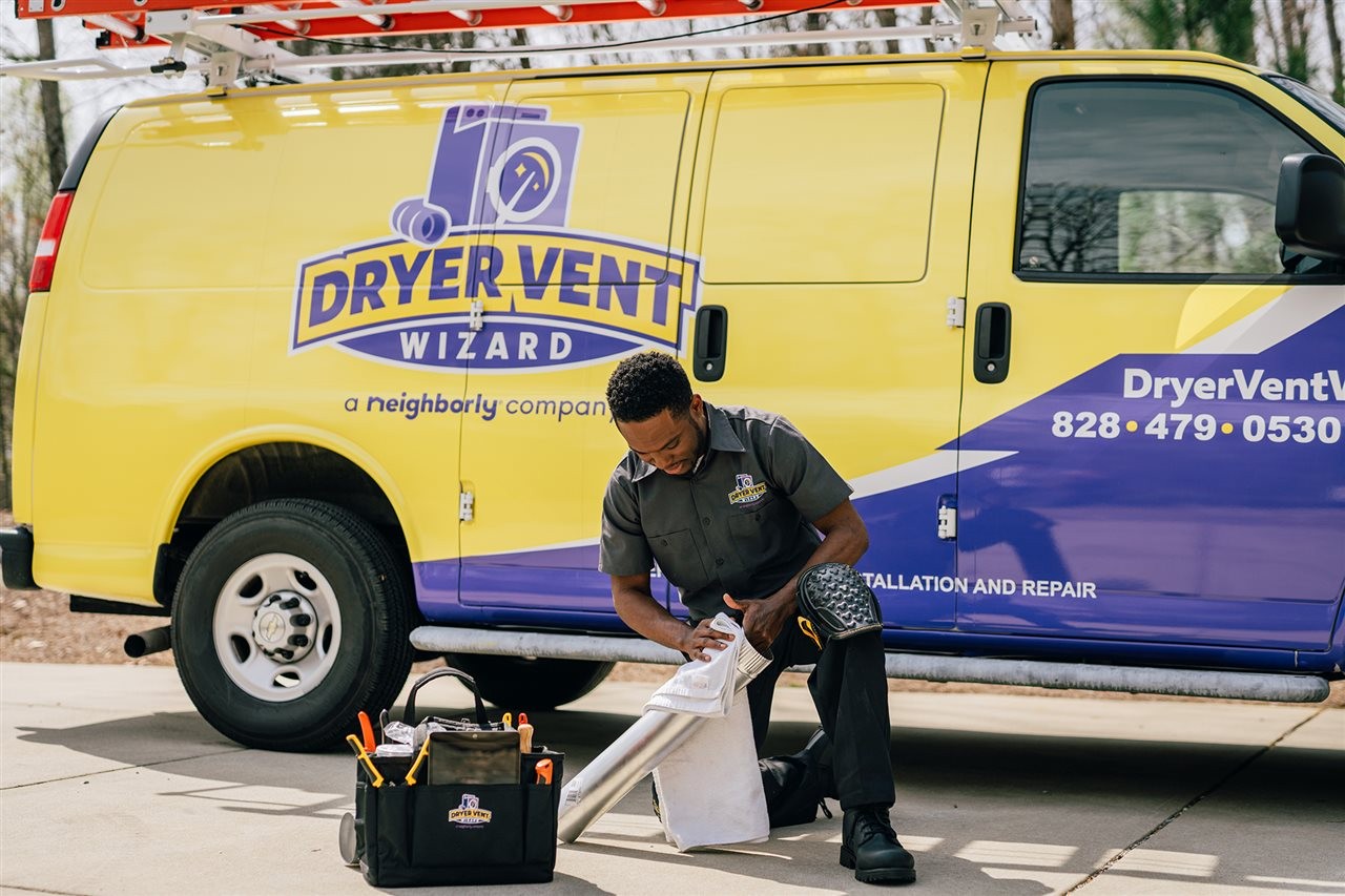 Dryer Vent Wizard service representative fixing and issue with a customer's dry vent outside of this truck.