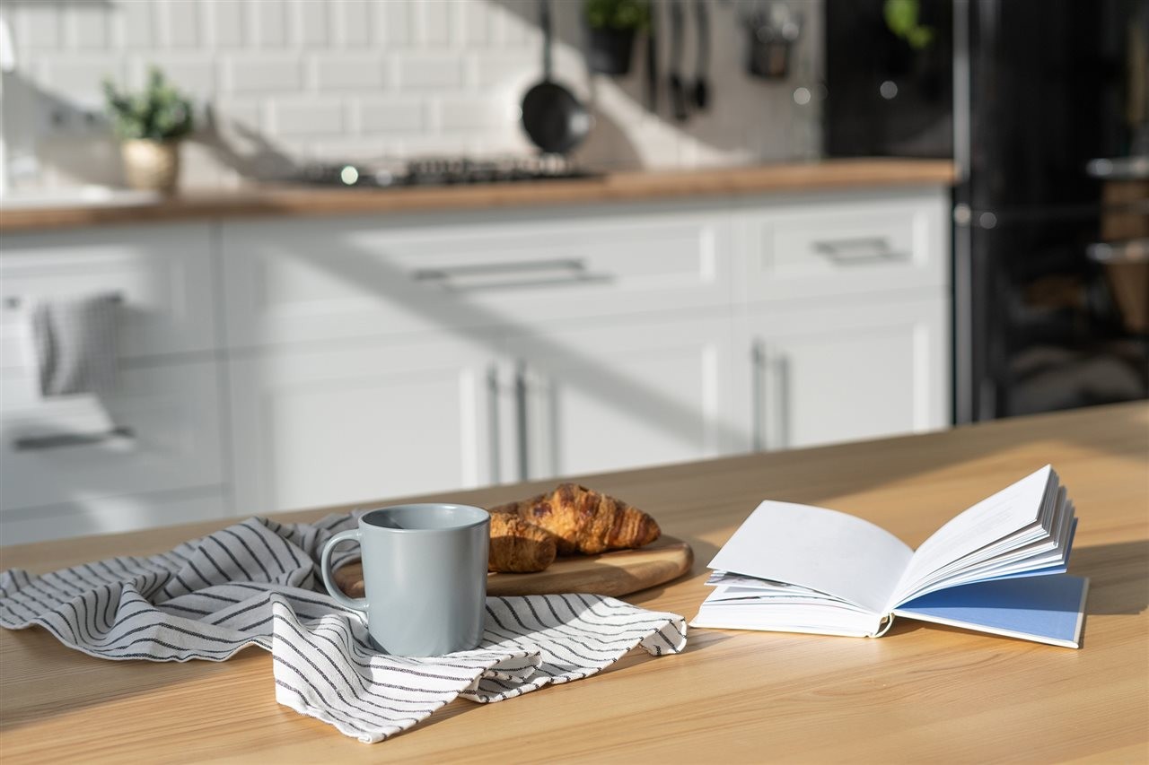 Coffee cup on the kitchen counter next to a book.