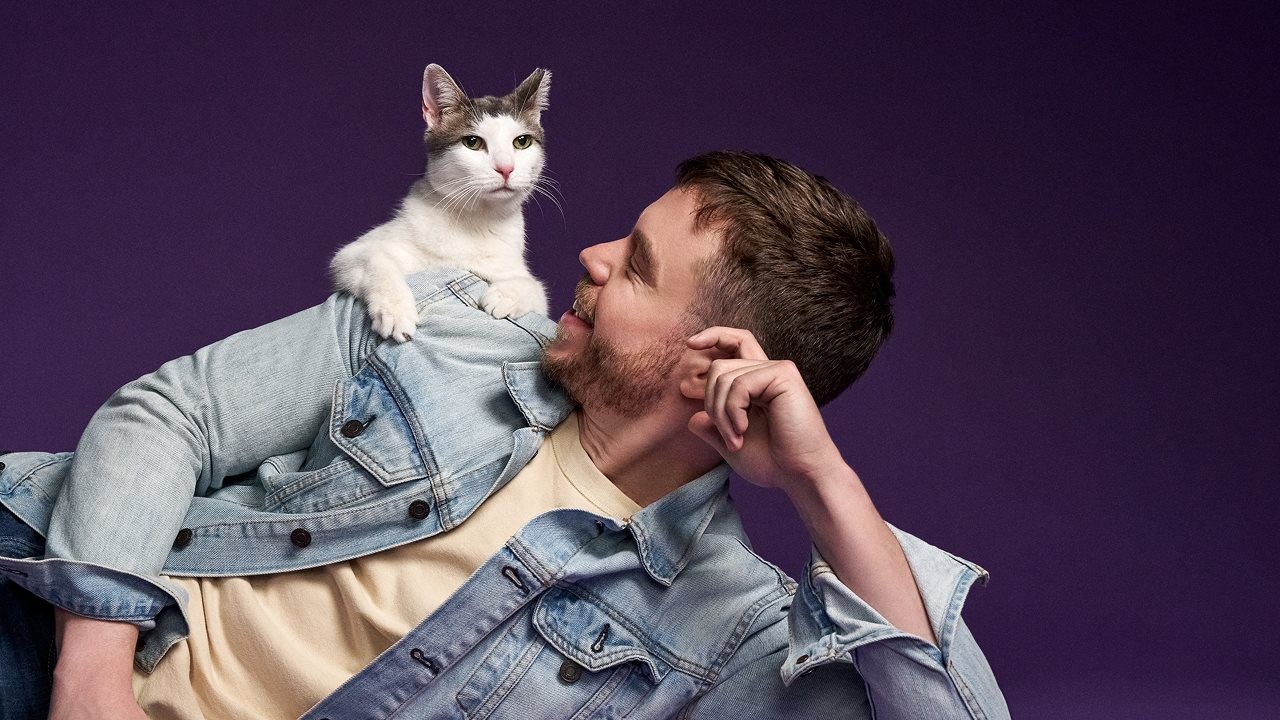 Cat dad laying on his side with cat on his shoulder.