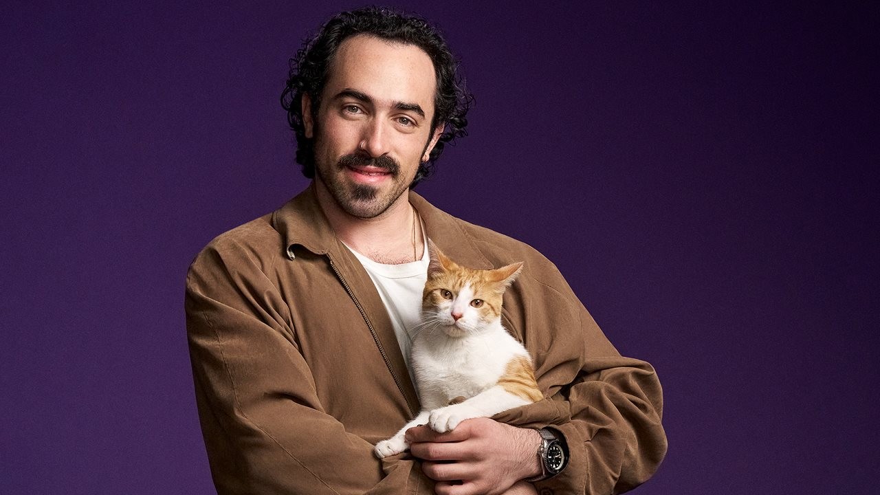Cat dad holding cat in front of him.