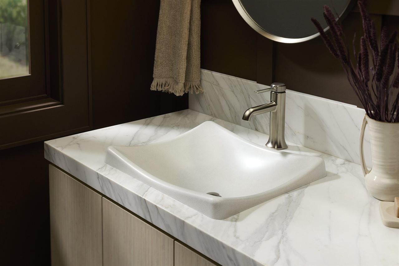A white rectangular vessel sink on a marble countertop.