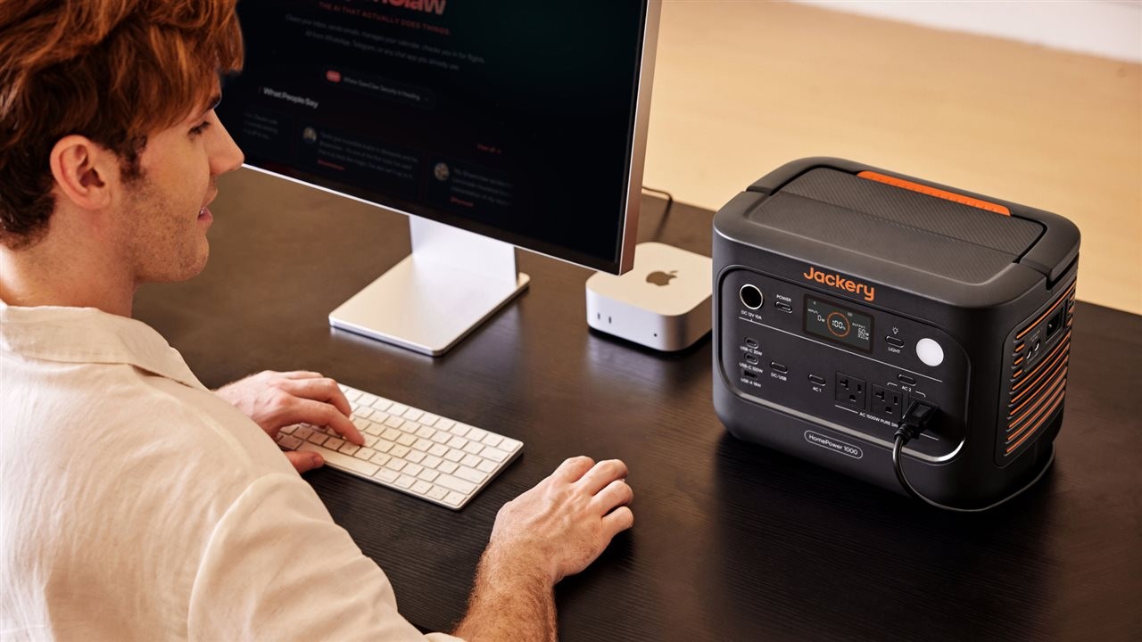 Man working on his computer on a desk next to the Jackery HomePower 1000.